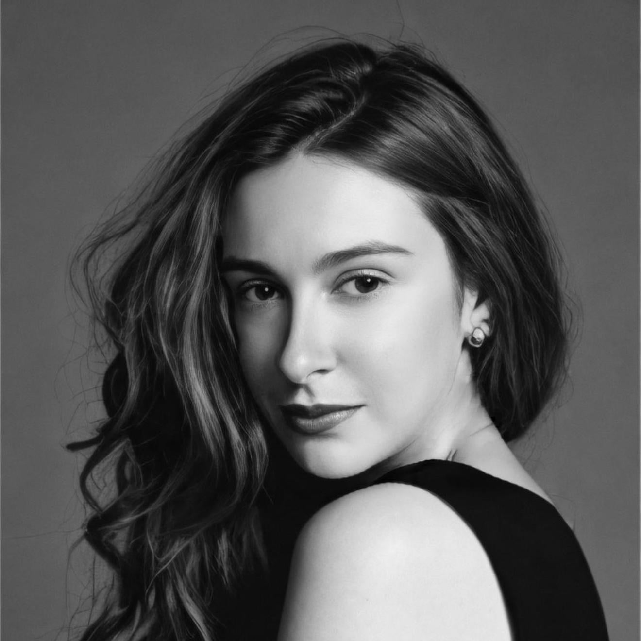 Black and white portrait of a woman with wavy hair against a gray background